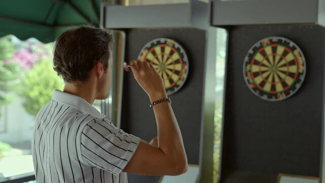 Young caucasian man throwing darts in cafe.The young man who hits her target with the darts she throws, experiences the happiness of success.