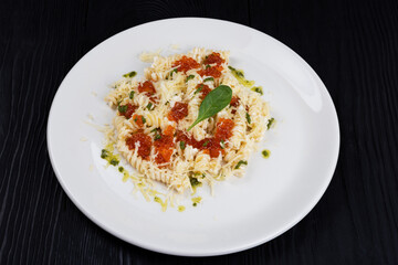 Pasta with red caviar on black wooden background