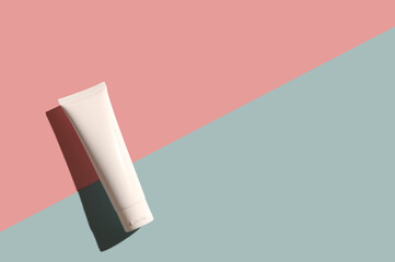 White container of cosmetic cream on a pink and blue background.