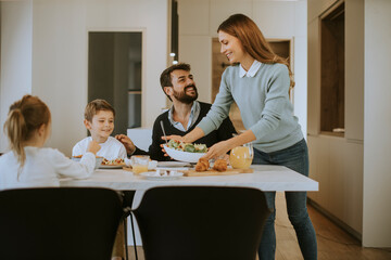 Young happy family talking while having breakfast at dining table