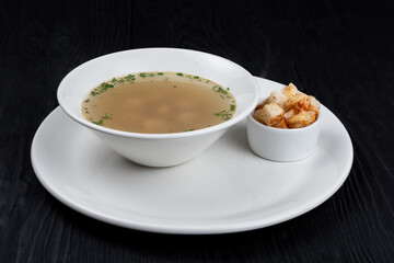 Chicken soup bouillon in a plate with chicken meatballs and croutons