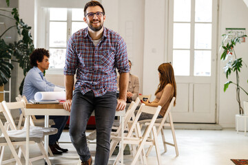 Fototapeta premium Portrait of casually dressed businessman sitting on desk in his office.