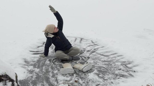 Winter. A girl does simple yoga exercises sitting in warm clothes and taking off her shoes on the ice of a forest lake. Siberia.