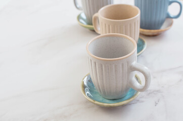 multicolored ceramic cups and plates on white marble table