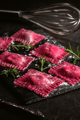 Beetroot ravioli with goat cheese on dark background
