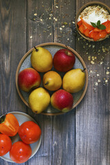 apples, pears, persimmons and yogurt with muesli on a wooden background