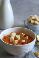 pumpkin cream soup with croutons, pumpkin seeds in a white bowl, milk bottle on a light background