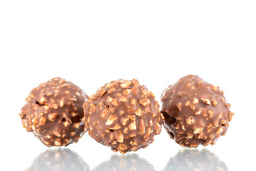 Three sweet chocolate candies with nuts, close-up, isolated on white.