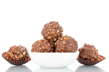 Several sweet chocolate candies with nuts with white ceramic dishes, close-up, isolated on white.