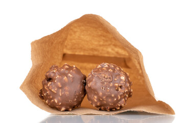 Two sweet chocolate candies with nuts in a paper bag, close-up, isolated on white.