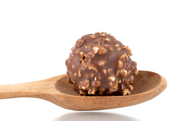 One sweet chocolate candy with nuts with a wooden spoon, close-up, isolated on white.