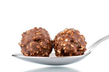 Two sweet chocolate candy with nuts with a metal spoon, close-up, isolated on white.