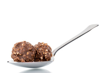 Two sweet chocolate candy with nuts with a metal spoon, close-up, isolated on white.