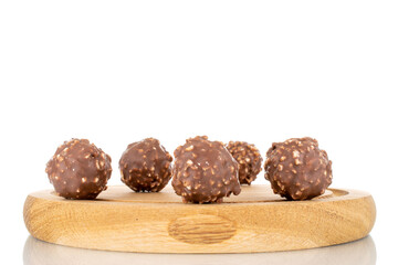 Several sweet chocolates with nuts on a wooden tray, close-up, isolated on white.