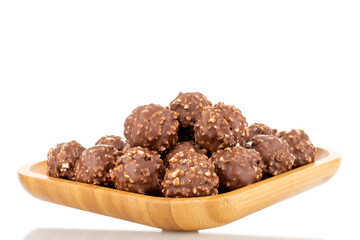 Several sweet chocolates with nuts on a wooden tray, close-up, isolated on white.