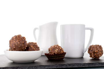 Several sweet chocolate candies with nuts with white ceramic dishes, close-up, isolated on white.