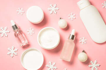 Obraz na płótnie Canvas Winter cosmetic, skin care product. Cream, serum, tonic with winter decorations. Top view on pink background with copy space.