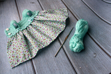 Fototapeta na wymiar Crochet dress for a doll made of cotton yarn . Home needlework made of thread.