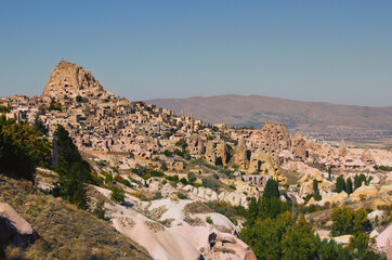 Amazing aerial landscape view of ancient Ortahisar cave city. Blue sky background. Popular travel destination in Turkey. UNESCO World Heritage Site. Autumn sunny day panorama
