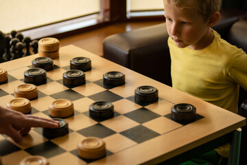Father teaches his son to play checkers. The child is focused. Family Spend time together.Chessboard with checkers. Board game. Hobby. checkers on the playing field for the game.