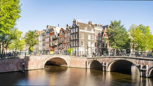 Amsterdam, Netherlands, Timelapse - Amsterdam city buildings timelapse at canal waterfront during a sunny day