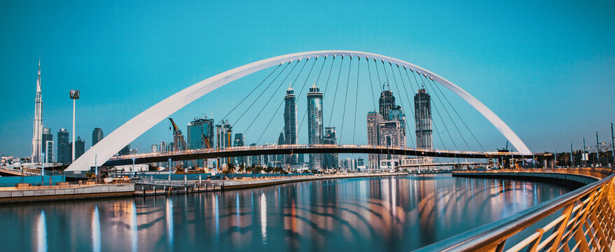 colorful sunset over Dubai Downtown skyscrapers and the newly built Tolerance bridge as viewed from the Dubai water canal