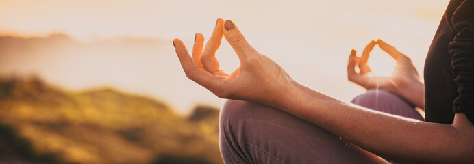 woman doing yoga in beautiful nature background at sunset or sunrise, focus on hand - mindfulness...
