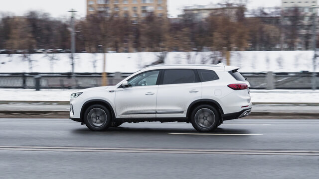 White Chery Tiggo 8 Plus SUV car at winter city street in motion