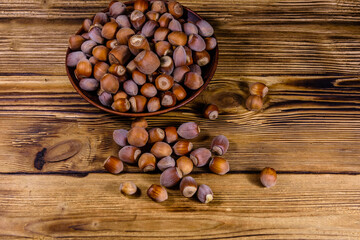 Plate with pile of hazelnuts on a wooden table