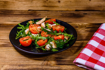 Roasted chicken breasts and salad with arugula and cherry tomatoes in a black plate