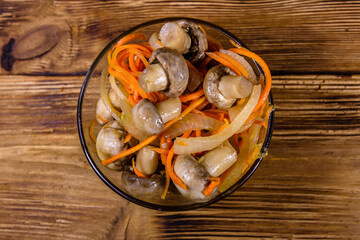Canned mushrooms with carrot and onion in a ceramic bowl. Top view