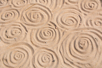 Fototapeta na wymiar Swirl pattern on the sand. Hand drawn swirls on the sandy beach