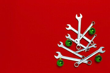 Christmas tree made of wrenches decorated with green balls on red background. New Year banner with...