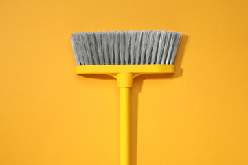 Plastic broom on yellow background, top view