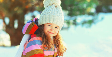 Winter portrait of happy smiling little girl child outdoors on snowy background