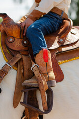 Person riding a horse with a cowboy boot in the stirrups of the saddle