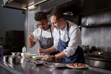 Diverse colleagues cooking salad in kitchen