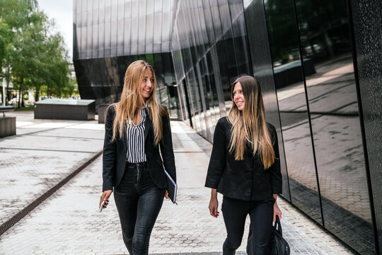 Cheerful businesswomen walking on street