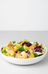 Italian shrimp salad with oranges, green lettuce, red onions, olive oil and sesame seeds on a white background, copy space. Selective focus