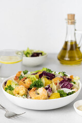 Italian green mix salad with prawns, red onions, oranges and sesame seeds on a white background, copy space. Green salad with shrimps on a white background. Healthy food concept, diet.