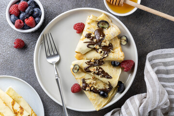 French breakfast with pancakes, berries, honey on a dark background, top view. The concept of the week of pancakes, Russian carnival