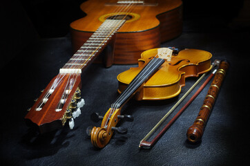 Guitar, violin with bow and pipe on a dark background. Light brush applied.