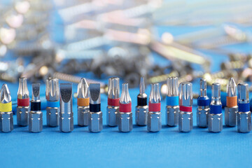 Screwdriver bits and fasteners of various kinds on a blue background. Copy space.
