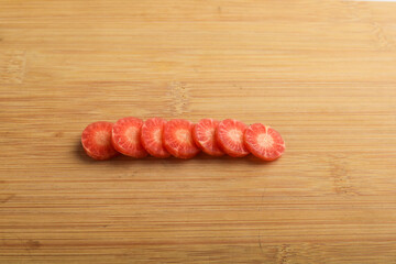 Fresh carrot slices on wooden board.