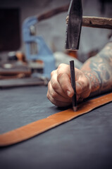 Handicraftsman performs leather working for a new product in leather shop
