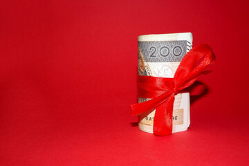 on the right are two hundred Polish zlotys tied with a red ribbon on a red background. side view. a...