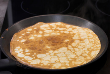 Frying pan with pancake isolated over white background