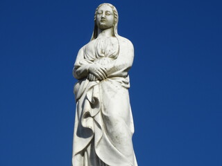 Fototapeta na wymiar Estátua antiga de marmore com céu azul ao fundo, em um belo cemitério antigo. 