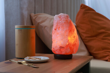 Himalayan salt lamp, air ionizer and accessories on nightstand in bedroom