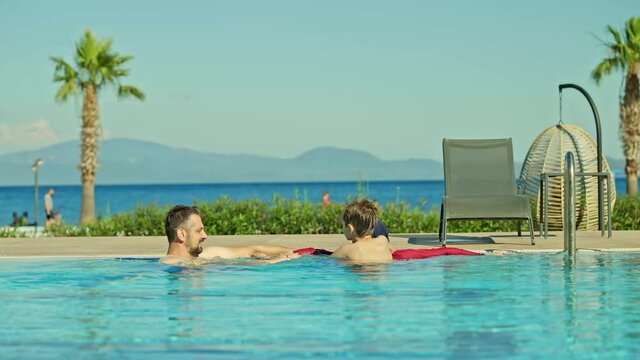 A young woman wearing a hijab swimsuit is swimming in the pool with her husband and young son. Happy young couple having fun in the pool with their son.A happy family is enjoying their vacation.